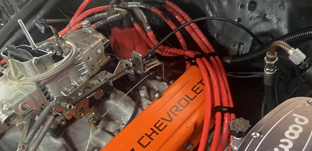 Chevrolet engine with orange valve cover, carburetor and red ignition wires