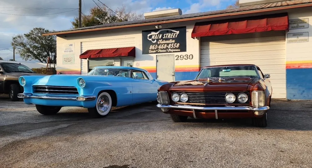 Two classic cars parked outside the Harrell's Main Street Automotive shop