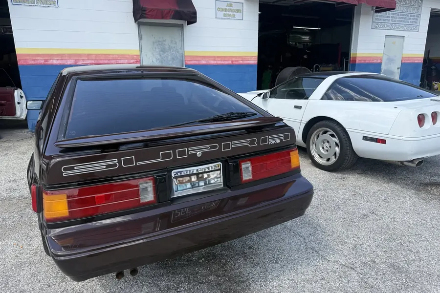 Dark coupe from the rear, beside the shop